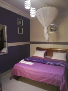 um quarto com uma cama com lençóis roxos e um espelho em Residence Les Calanques em Dakar