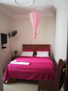 a bedroom with a pink bed with a pink umbrella at Residence Les Calanques in Dakar