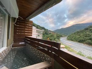 einen Balkon mit Blick auf den Fluss und die Berge in der Unterkunft Cheng-Ping Hot Spring Inn in Wenquan