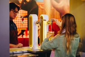 kobieta stojąca w barze trzymająca drinka w obiekcie Ok Hostel Madrid w Madrycie