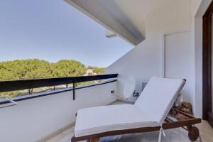 ein weißes Zimmer mit einem weißen Stuhl und einem Fenster in der Unterkunft Ténis Golf Mar - 1 bedroom Apartment - Vilamoura in Vilamoura