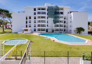 ein großes Gebäude mit einem Pool vor einem Gebäude in der Unterkunft Ténis Golf Mar - 1 bedroom Apartment - Vilamoura in Vilamoura