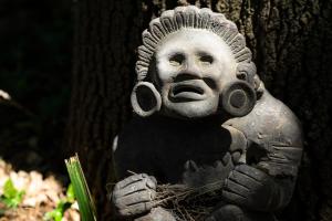 a statue of a man sitting on a tree stump at Posada Colibri - Hotel & Spa in San Juan Teotihuacán