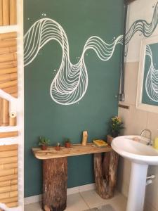 baño con lavabo y ducha con un mural de olas en Vila da Mata - Bambu House en Alto Paraíso de Goiás