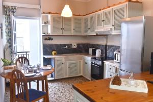 una cucina con armadi bianchi, tavolo e frigorifero di Apartment in Koomkapi a Chania