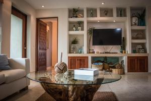 a living room with a glass table and a tv at Residencial Los Mangos - Departamento 205 in Zihuatanejo