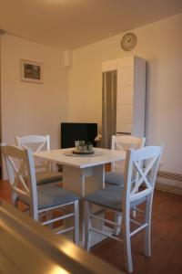 tavolo da pranzo bianco con sedie e orologio sul muro di STUDIO APARTMAN MARIA a Čavle