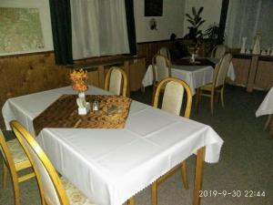 un comedor con 2 mesas y sillas con mantel blanco en Pension Helene s mini pivovarem, en Kytlice