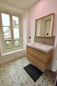 Łazienka z umywalką i lustrem oraz 2 oknami w obiekcie LA LOGE DU MONTCEL - T2 -1er étage w mieście Auvers-sur-Oise