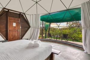 um quarto com uma cama e uma grande janela em Glamping Serra da Canastra - Casinha de Hortelã - Domo Jaboticaba em Delfinópolis