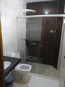 a bathroom with a toilet and a glass shower at Hotel Kanaan in Pimenta Bueno