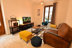 a living room with a couch and a tv at LE COTTAGE AUVERSOIS - Rdc -T2 - in Auvers-sur-Oise