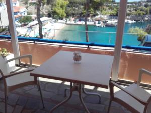 a table and chairs on a balcony with a view of the water at Rooms Apostolis in Patitiri