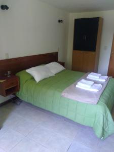 Un dormitorio con una cama verde con toallas. en Don Alfonso Departamento, en San Carlos de Bariloche