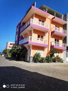 budynek z różowym i fioletowym balkonem na ulicy w obiekcie Casa Celeste w mieście Ponta do Sol