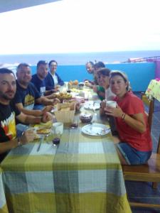 een groep mensen die rond een tafel zitten te eten bij Casa Celeste in Ponta do Sol