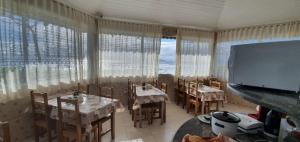 a dining room with tables and chairs and a large screen at Hotel Nils in Itapoa