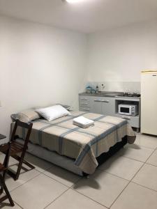 uma pequena cozinha com uma cama e um frigorífico em Kitnet 1 mobiliada no centro de Torres a 600m da Praia Grande em Torres