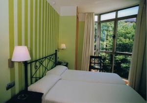 1 dormitorio con cama blanca y ventana en Hotel la Concha de Suances, en Suances