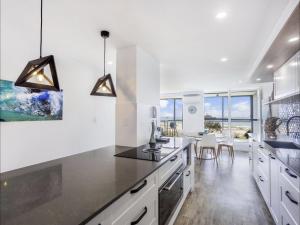 a kitchen with white cabinets and black counter tops at Kirra Waves in Gold Coast