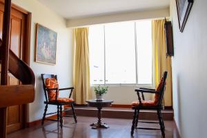 a living room with two chairs and a table and a large window at Hotel Ivansino Inn in Chimbote