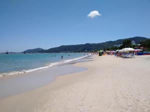 a beach with a lot of people and the water at Canto dos Pássaros Apartamentos in Florianópolis