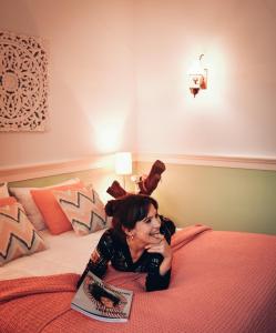 a woman laying on a bed with a book at Chalet Santa Iria in Santarém