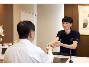 a man shaking hands with a man sitting at a table at Benikea Calton Hotel Fukuoka Tenjin in Fukuoka