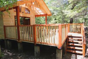 a wooden cabin with a porch in the woods at Llaima Camp in Curacautín