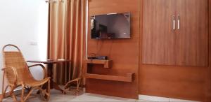 Habitación con mesa y TV en la pared. en Cassells Jungle Resorts Thekkady, en Vandiperiyār