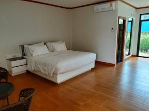 um quarto com uma cama branca e piso em madeira em Baan Anong Hotel em Aranyaprathet