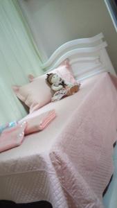 a teddy bear laying on top of a pink bed at CASA AZUL 1 in Foz do Iguaçu