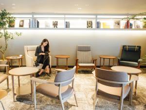 a woman sitting in a room with chairs and tables at NOHGA HOTEL UENO TOKYO in Tokyo