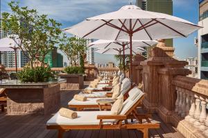 een rij ligstoelen met parasols op een dak bij Anik Palace Hotel in Phnom Penh