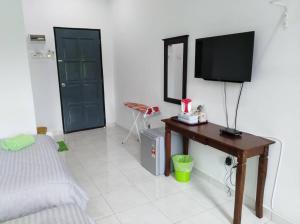 1 dormitorio con 1 cama y mesa con TV en D' Surya Lavender Inn en Pantai Cenang