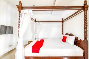a bedroom with a canopy bed with red pillows at RedDoorz Plus near Lempuyangan Station 4 in Yogyakarta