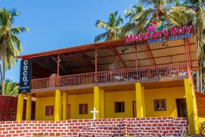 a yellow building with a sign on it at Mariners Bay Beach Resort in Arambol
