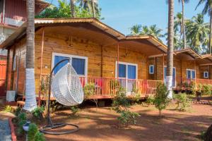 a wooden house with a porch and a surfboard in front at Mariners Bay Beach Resort in Arambol