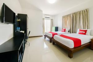 a bedroom with two beds and a flat screen tv at OYO 350 Mae Saeng Place in Si Racha