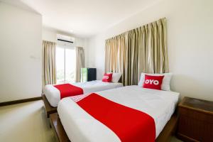 two beds in a hotel room with red and white sheets at OYO 350 Mae Saeng Place in Si Racha