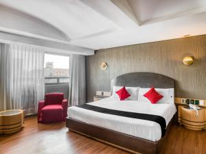 um quarto de hotel com uma cama e uma cadeira vermelha em Capital O Andrade, Mexico City em Cidade do México