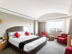 una habitación de hotel con una cama grande y sillas rojas en Capital O Andrade, Mexico City, en Ciudad de México