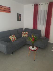 Sala de estar con sofá gris y mesa en Maison Laurencia - Appartement de l'étage, en Sainte-Anne