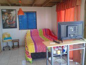 a bedroom with a bed and a desk with a tv at Habitaciones Gabriel in Horcón