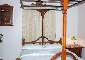a bedroom with a wooden canopy bed with white pillows at The Ferreiras in Mumbai