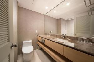 a bathroom with a toilet and a sink and a mirror at Jeju Sun Hotel & Casino in Jeju