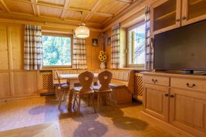 une salle à manger avec une table, des chaises et une télévision dans l'établissement Home in the Alps, à Racines