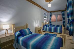 sypialnia z 2 łóżkami i lampką w obiekcie Dar Sidi Mfedal w mieście Szafszawan