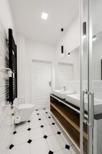 a white bathroom with a toilet and two sinks at Apartament SWEET TIME in Wrocław