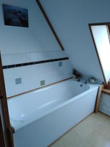 uma banheira branca na casa de banho com uma janela em au petit bonheur em Putanges